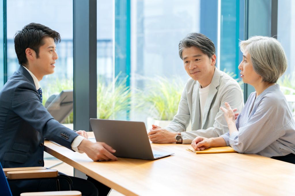 テーブルを囲んで話し合うシニア夫婦とビジネスパーソン
