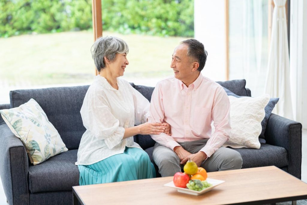 ソファに並んで座り、笑顔を浮かべるシニア夫婦