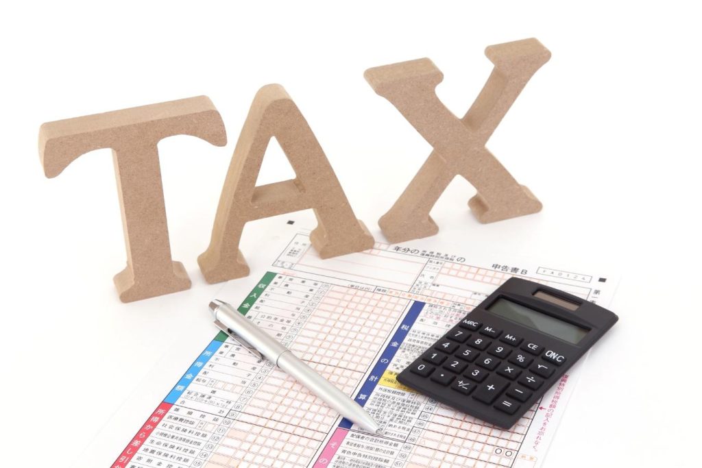 「TAX」の形のブロックと電卓、確定申告用の書類、ボールペン