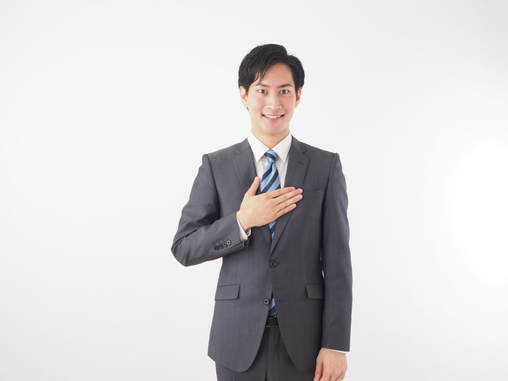 スーツ姿で胸に手を当てて微笑む男性