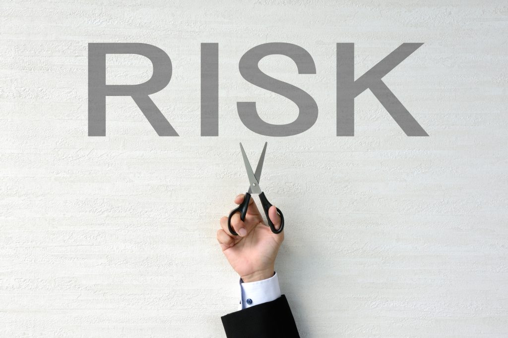 「RISK」の文字に向かってハサミを構える手