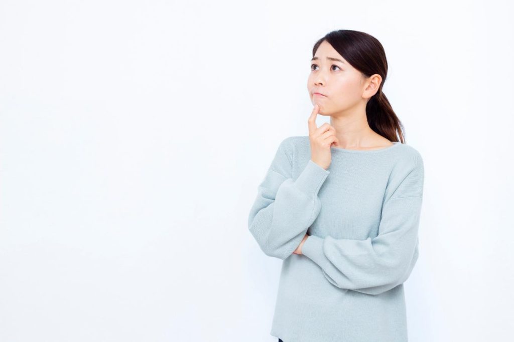 顎に指を当てて悩んでいる女性