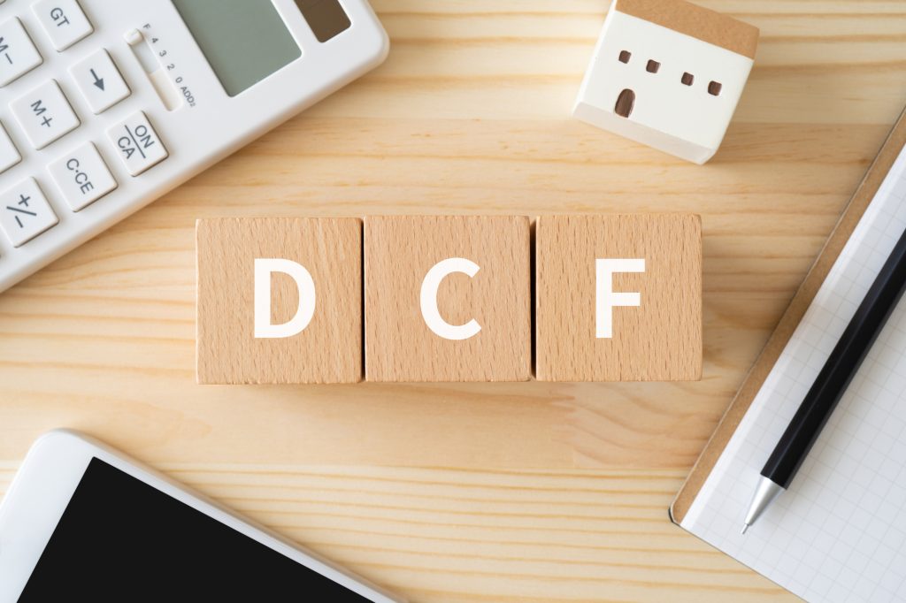  DCFと書かれたブロック、電卓、スマホ、建物の模型