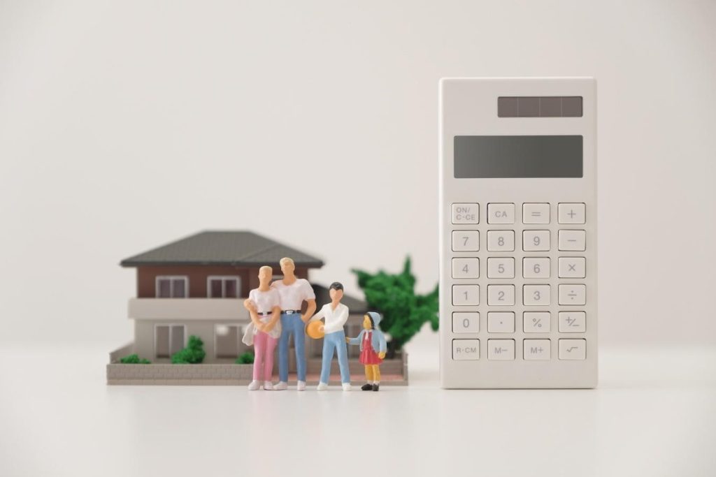 家と前に立つ4人家族のミニチュア、横に立てられた電卓
