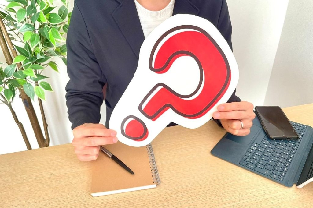 机で大きなクエスチョンマークのパネルを持っている人物