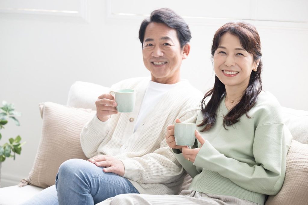 ソファに座り、マグカップを持ってくつろぐミドル夫婦