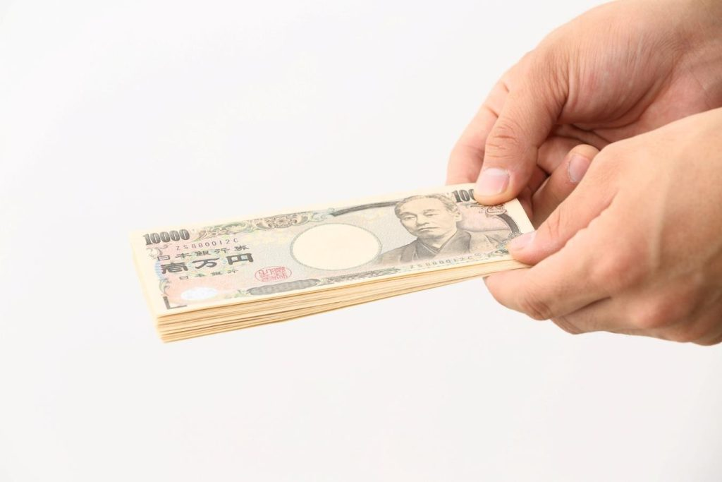 両手で1万円札の束を差し出している様子