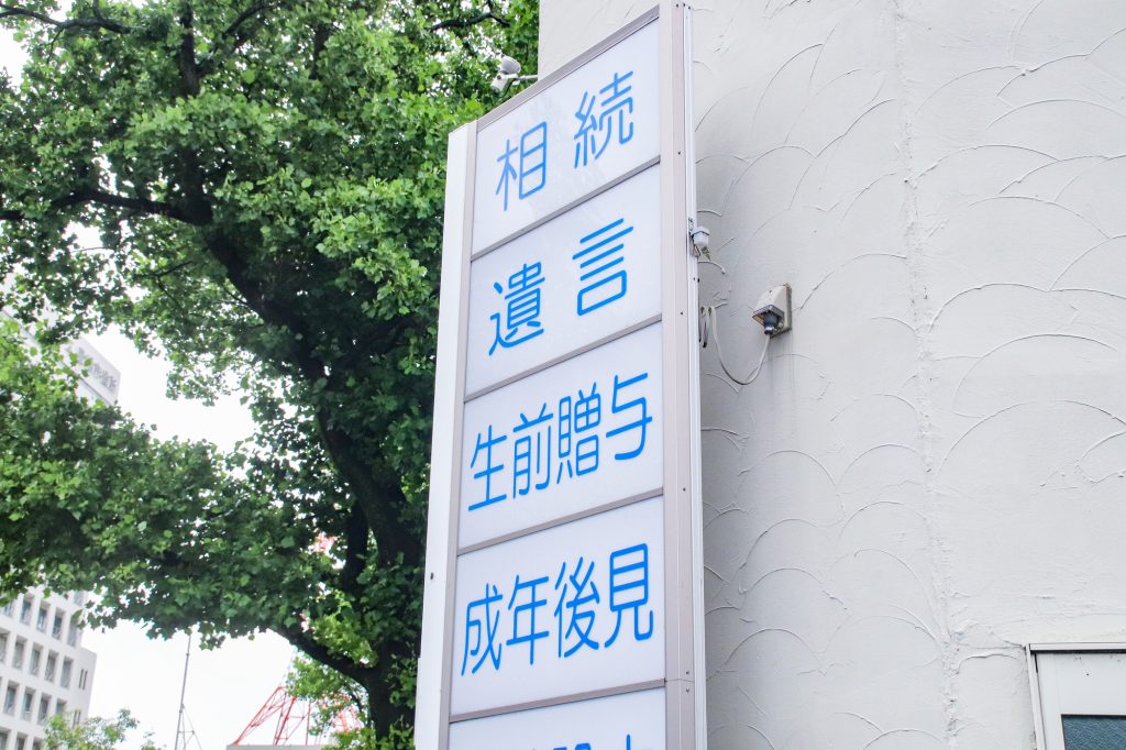 建物の外壁に設置された看板に、「相続」「遺言」「生前贈与」「成年後見」といった文字が並んでいる