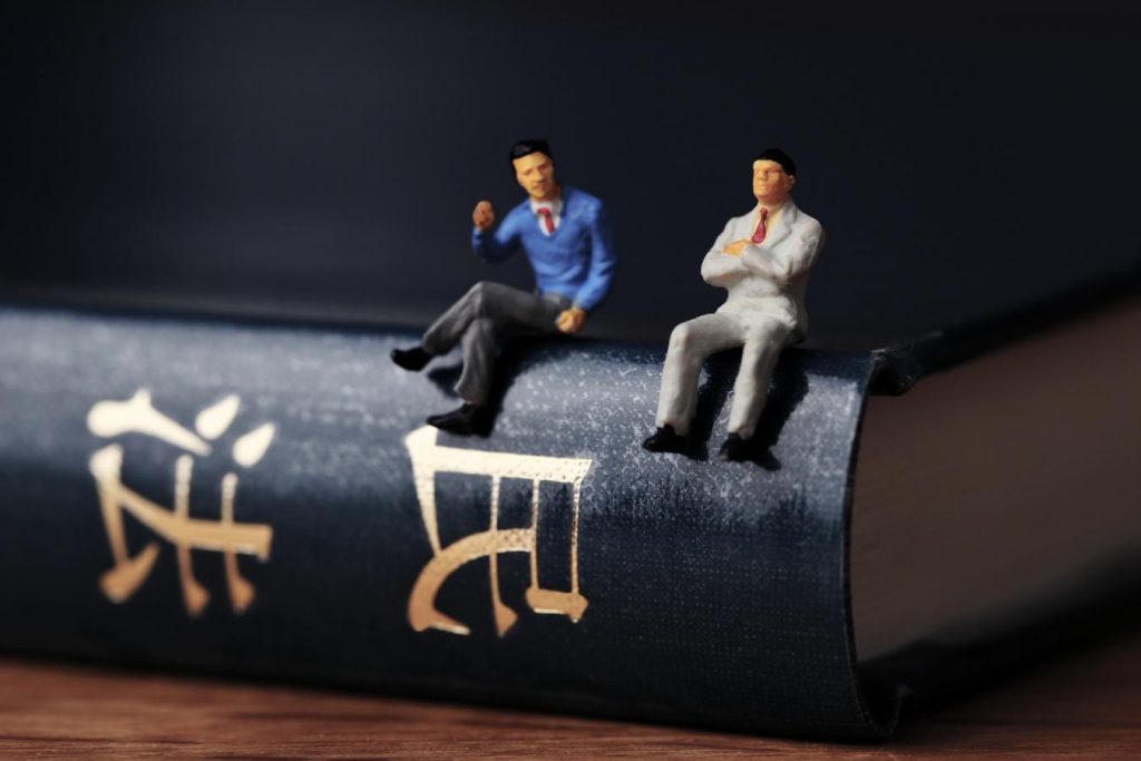 背表紙に「民法」と書かれた本の上で語り合うイメージ