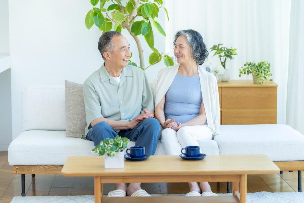 ソファに座り、笑顔で語り合うシニア夫婦