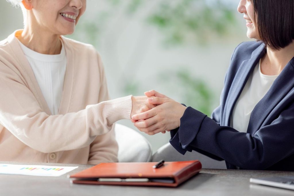 シニア女性と営業担当者が握手する様子