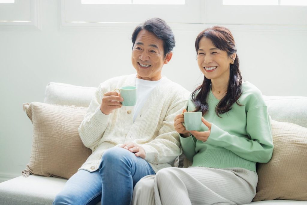 リビングのソファに座り、笑顔を浮かべる夫婦
