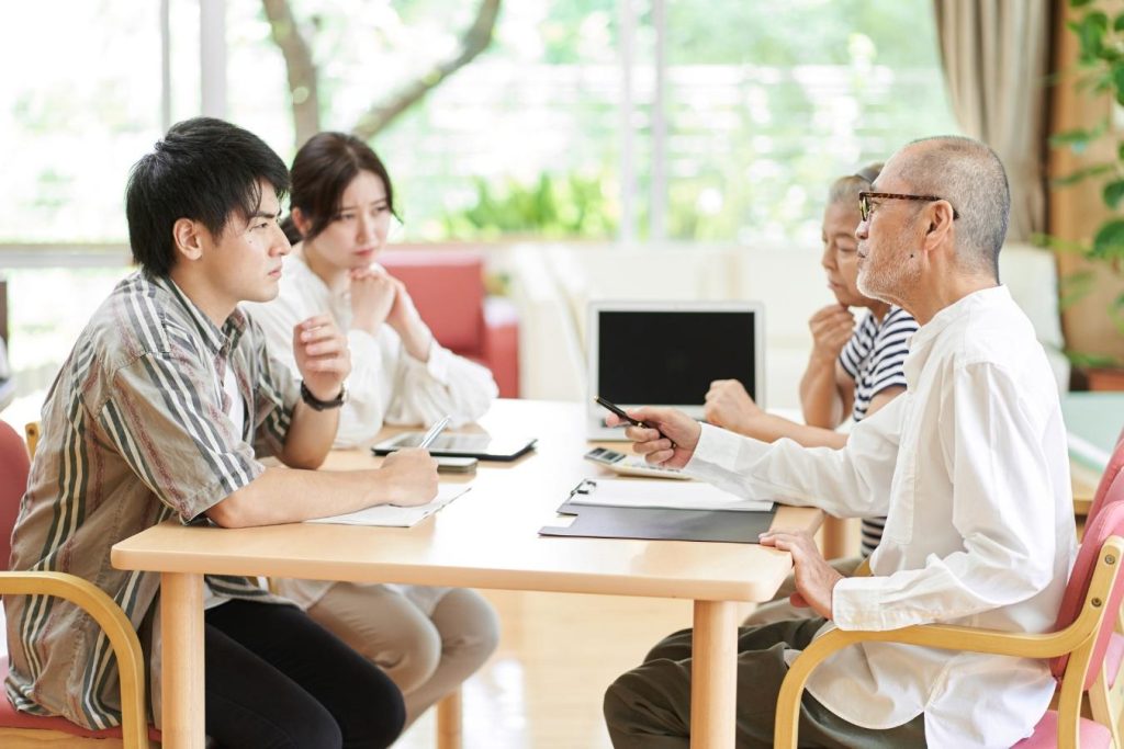 テーブルに向かい合って座り、話し合いをする4人の家族