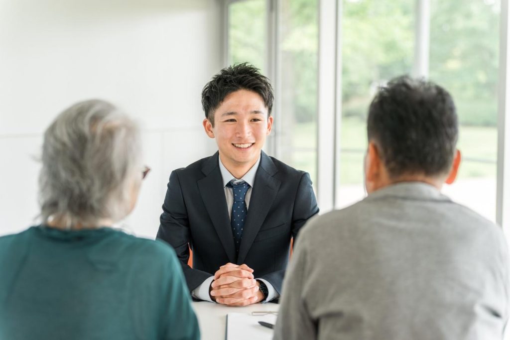 シニア夫婦の向かいに座り、相談に乗る営業担当者