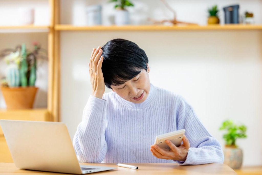 電卓で計算しながら頭を抱える女性