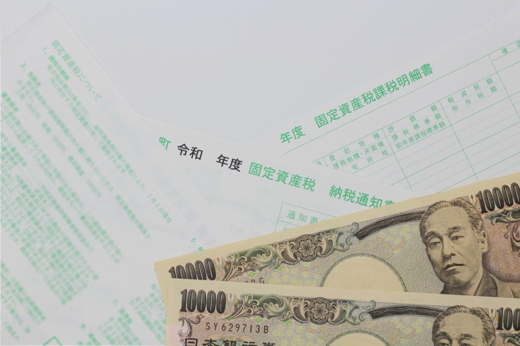 固定資産税の納税通知書と現金(1万円札)が並ぶイメージ