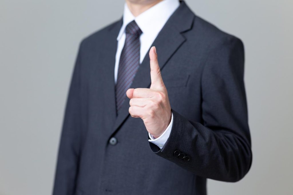 人差し指を立てるビジネスパーソン