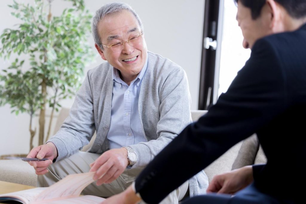 ソファに座り、営業担当者に相談するシニア男性