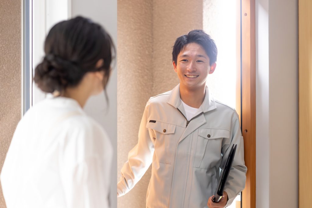 住宅を訪問した担当者が玄関先で住人と対応する、アフターサポートや点検をイメージした写真