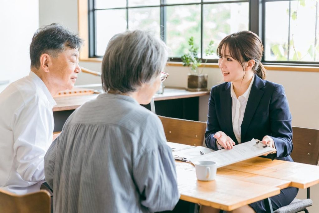 シニア夫婦に紙を見せながら説明するスーツ姿の女性