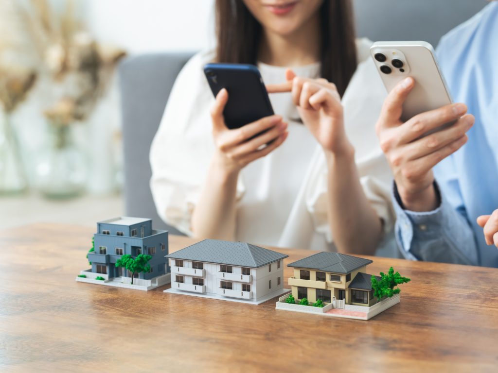 住宅模型とスマートフォンを操作する男女