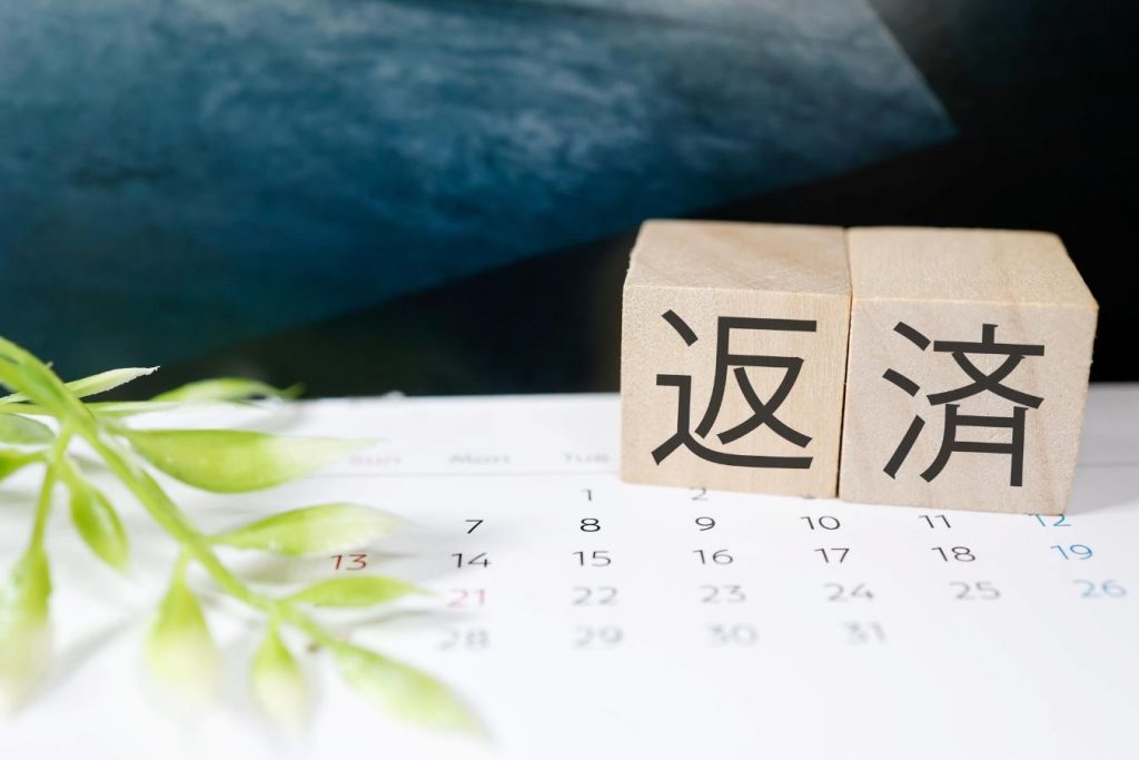 「返済」と書かれた木のブロックとカレンダー