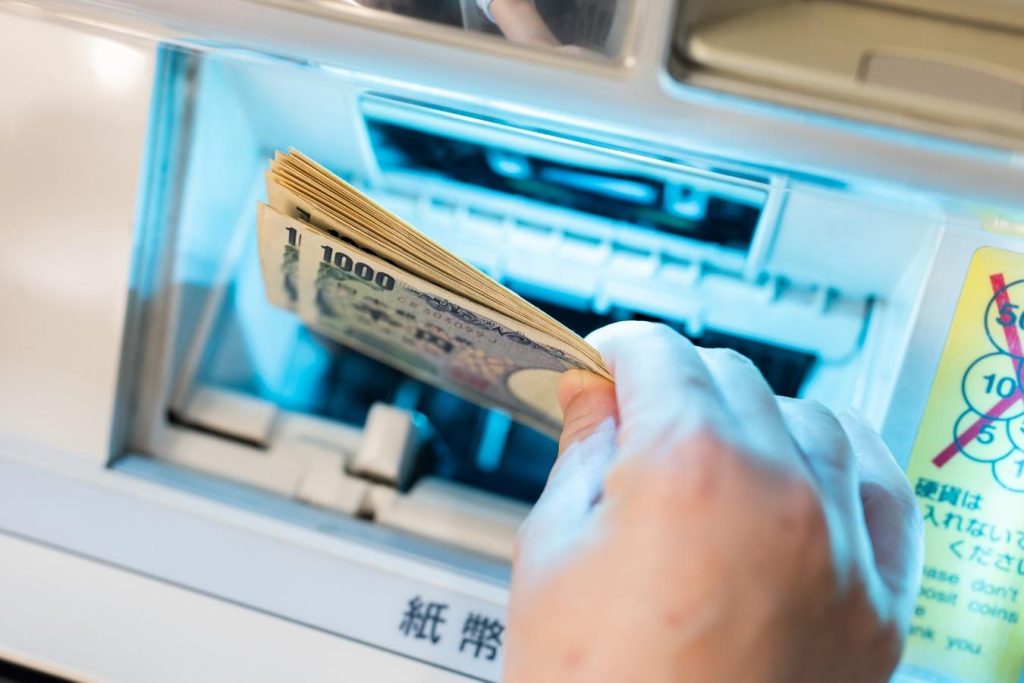 ATMで数枚の紙幣を入金する手元