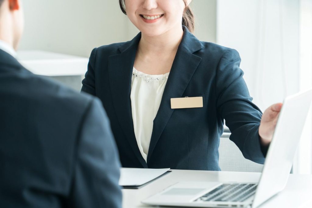 スーツ姿の女性の向かいに座り、相談する様子