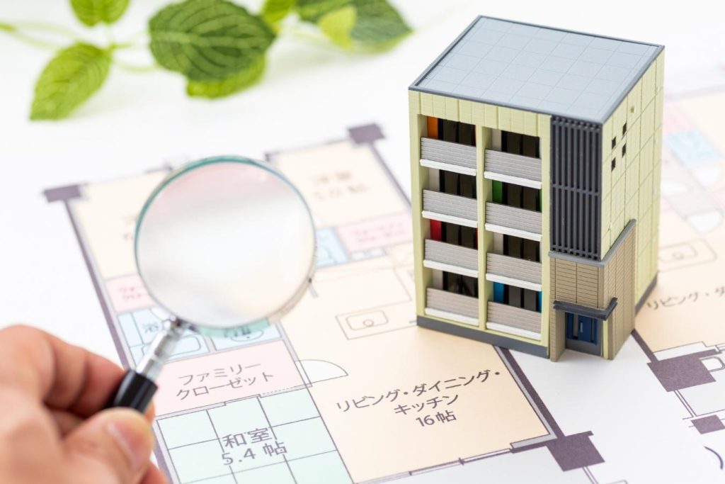 間取り図とマンションの模型を虫眼鏡で見る様子
