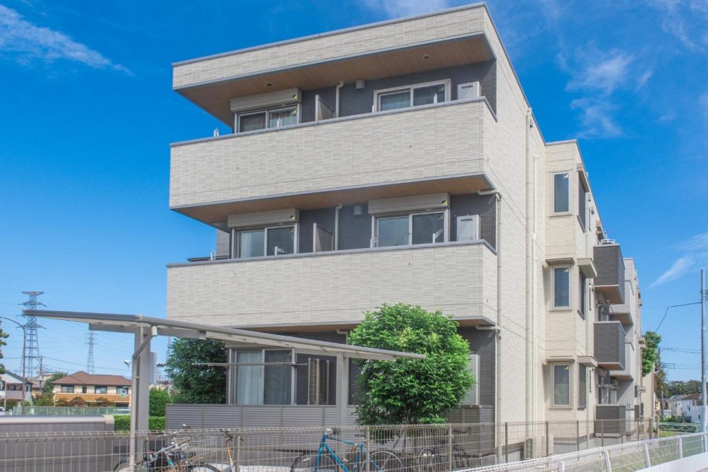 3階建てのマンションと青空