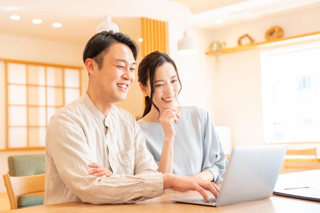パソコンの画面を見ながら笑顔を浮かべる夫婦。