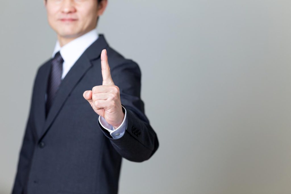 人さし指を立てるビジネスパーソン。