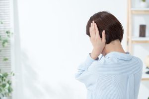 自宅のリビングで耳を塞ぐ女性の後ろ姿