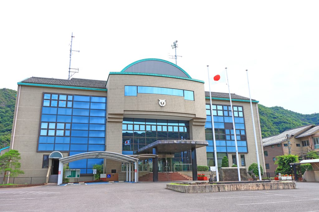 日本国旗が掲げられた、青いガラス窓が特徴的な役場（庁舎）の建物外観