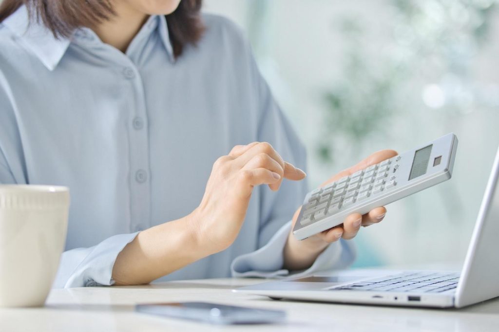 ノートPCの前で電卓を打つ手元