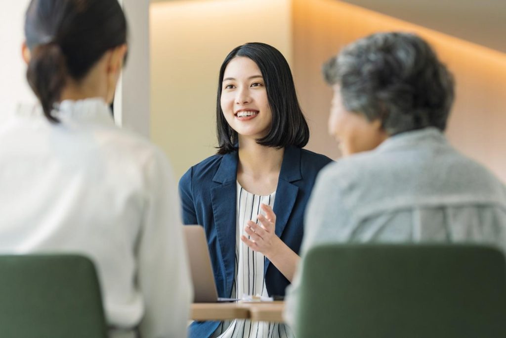女性2人の向かいに座り、説明をするスーツの女性