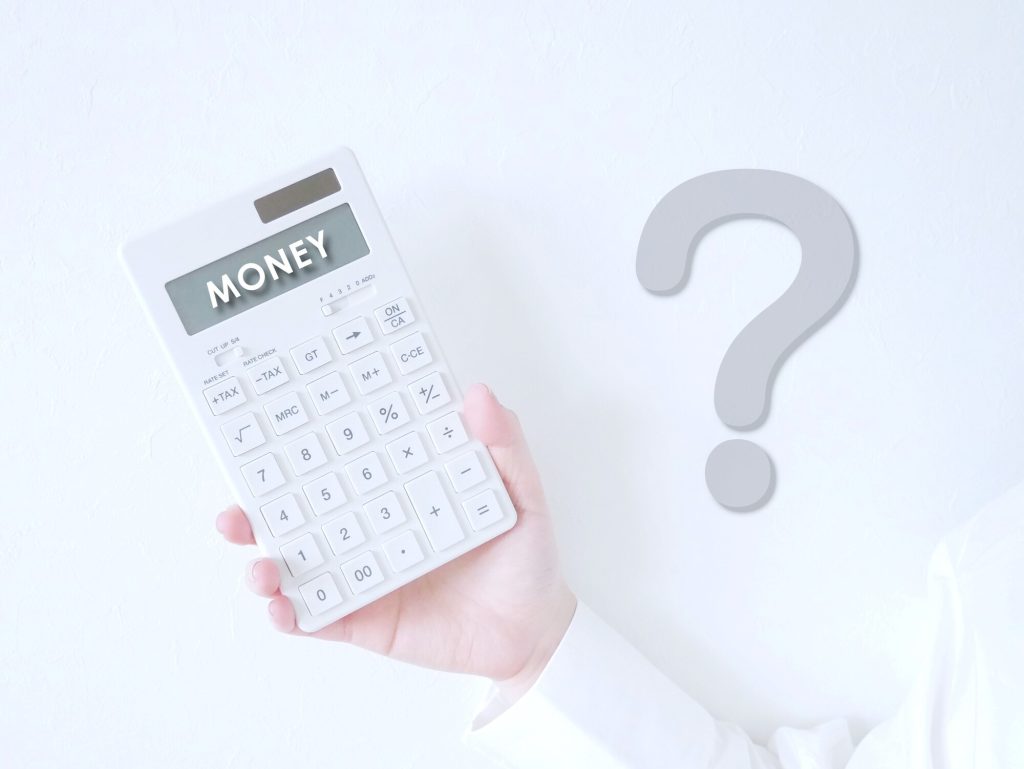 電卓を持つ手と大きな「？」マーク