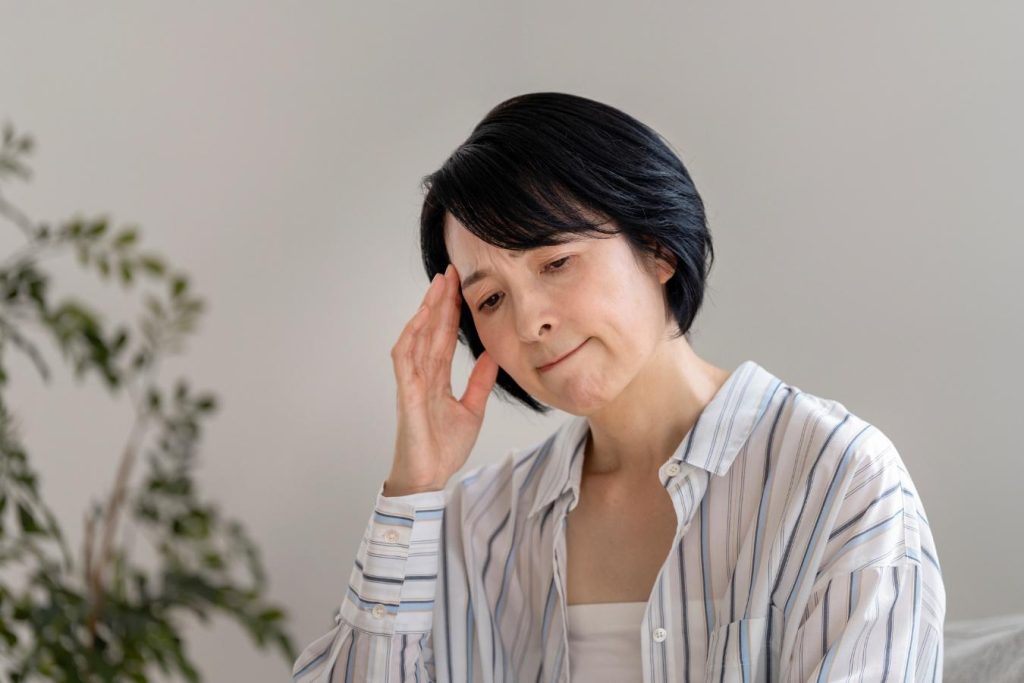 手でこめかみを押さえる女性。