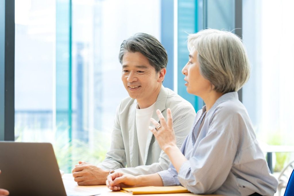 営業担当者との打ち合わせ中に笑顔を浮かべる夫婦。