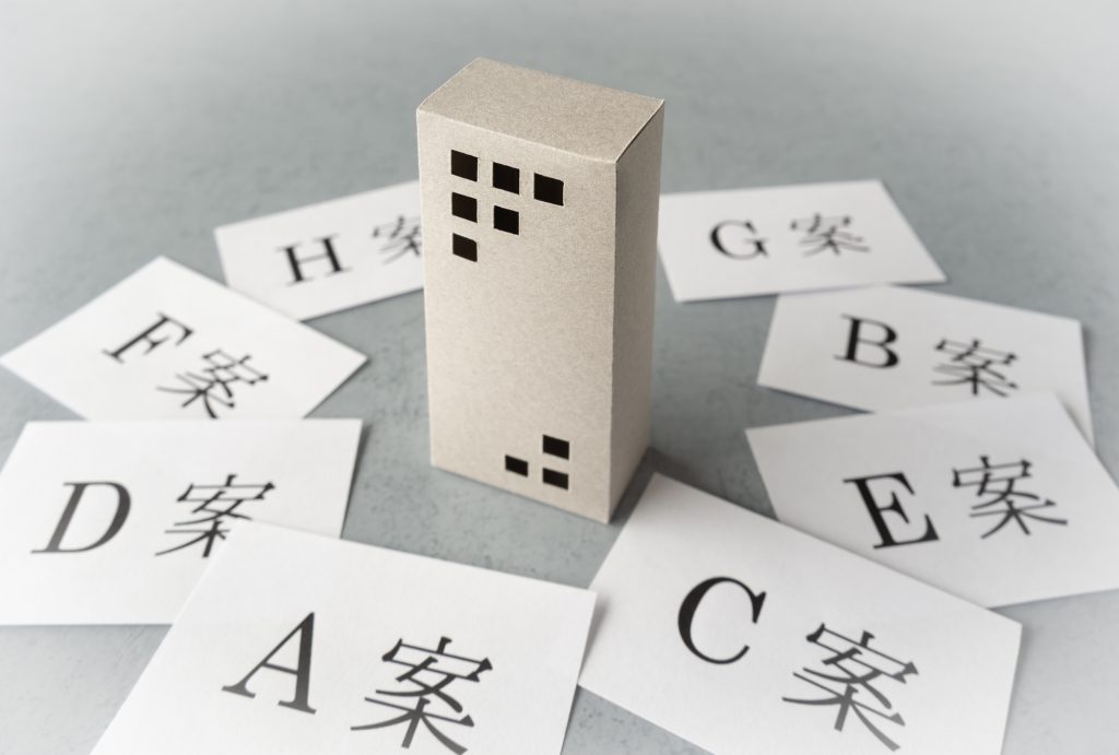 マンション模型を囲む複数の選択肢をイメージした比較検討の様子
