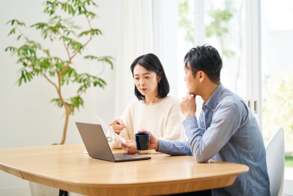 パソコンを見ながら書類を確認する夫婦