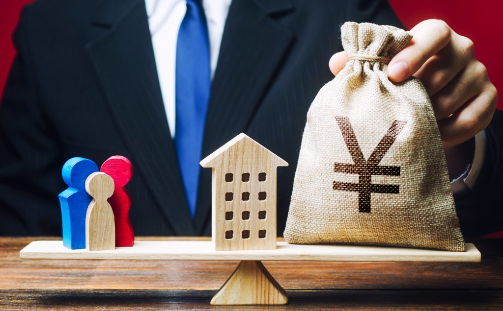住宅ローンの借入金額と返済負担をイメージした住宅模型と現金袋のイメージ