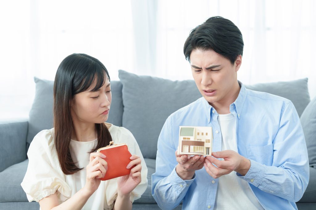 赤い財布を持つ女性と住宅模型を手にする男性