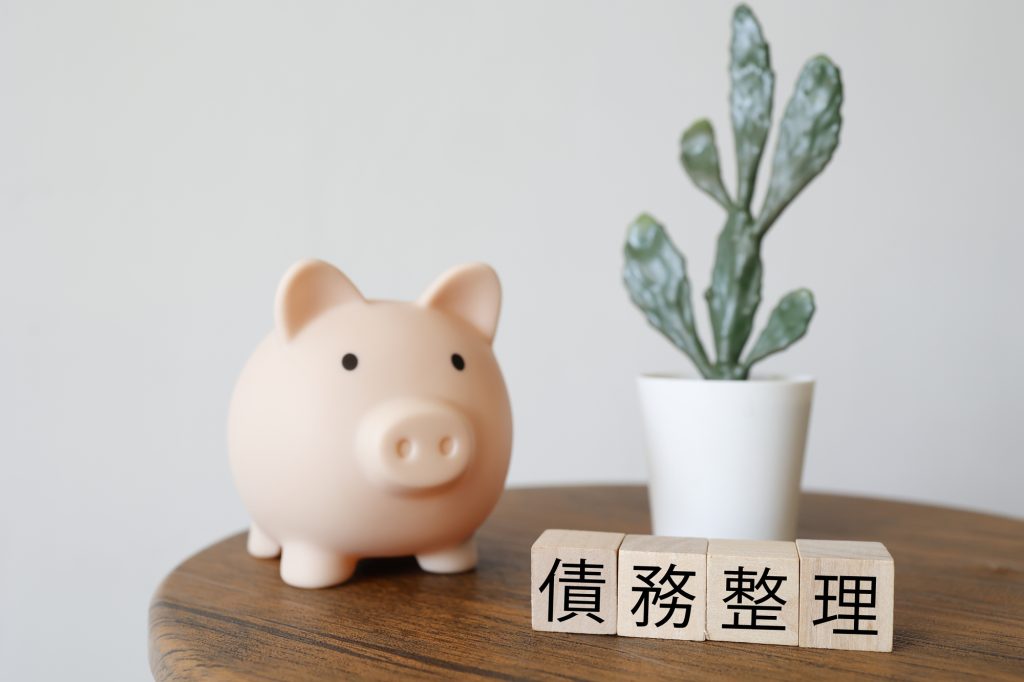 債務整理と貯金のイメージ、ブタの貯金箱と観葉植物