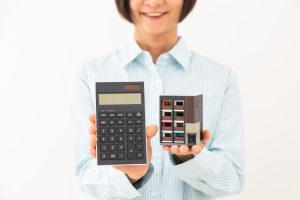 マンションの模型と電卓を持ってほほえむ女性