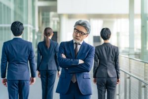 腕を組み、考え事をするシニアビジネスパーソン。