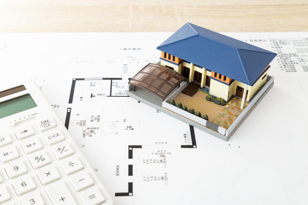 間取り図の上に置かれた住宅模型と電卓