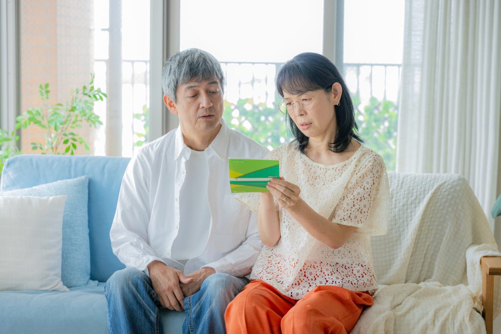 通帳を手にソファに座るシニアの男女