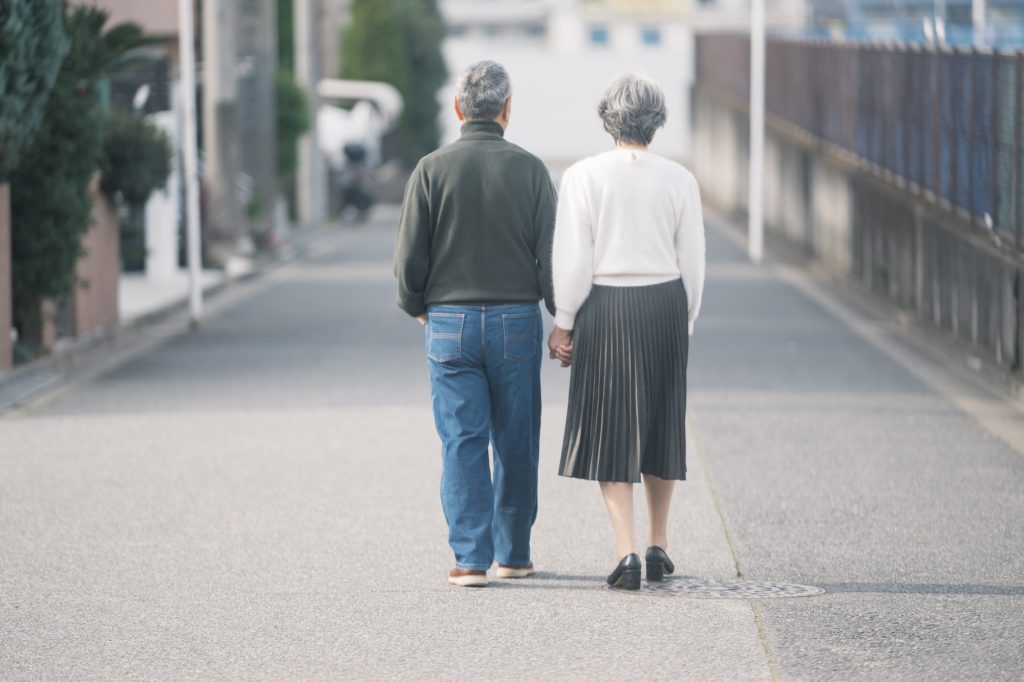 住宅街を手をつないで歩くシニア夫婦の後ろ姿