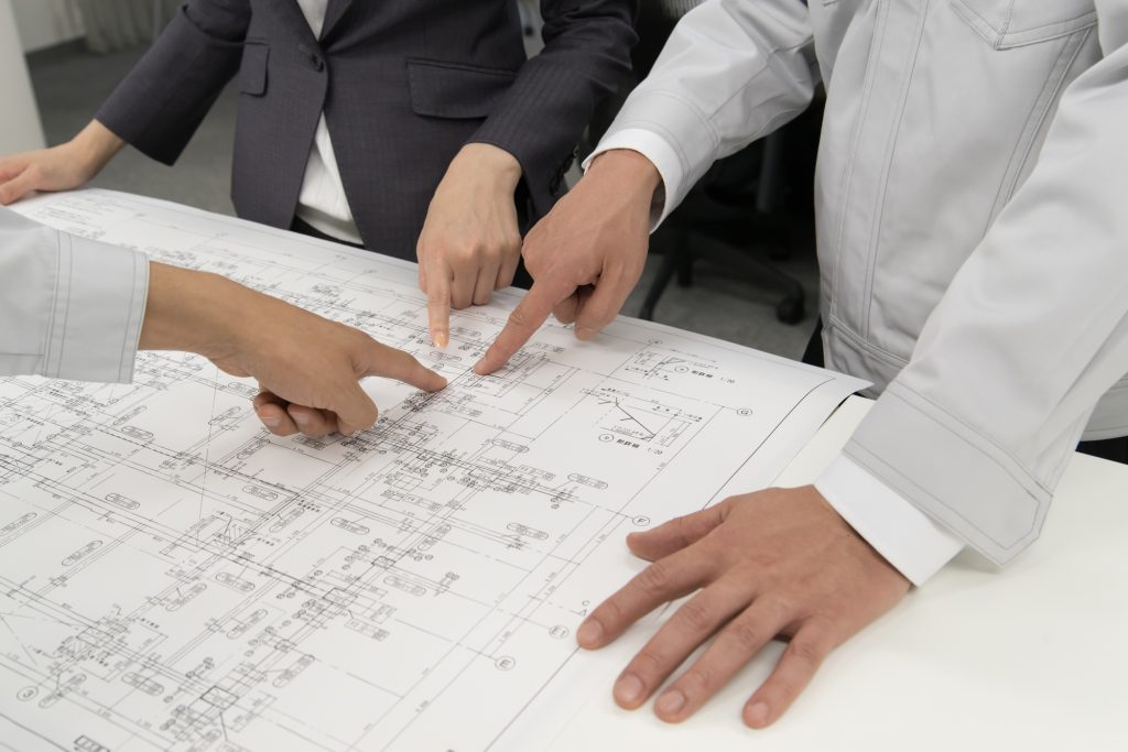 建築図面を確認しながら打ち合わせる技術者